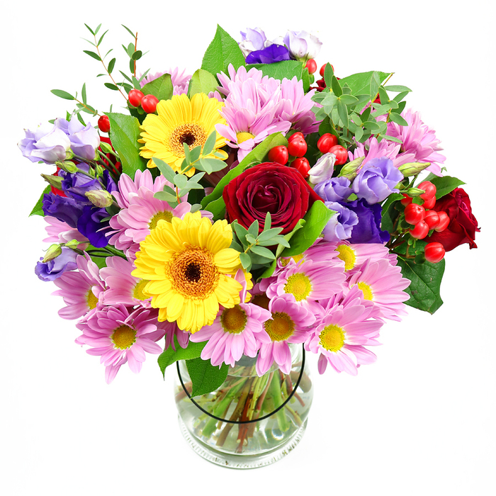 In this photograph, a colourful mixed bouquet is arranged with care in a transparent glass vase, positioned against a pristine white background that emphasises each bloom and stem. Dominating the centre, rich deep red roses with velvety, tightly layered petals provide a classic, romantic anchor, ideal for special occasions or heartfelt gestures in Barkingside. Nearby, two golden yellow gerbera daisies with dark brown-orange centres offer a bright, sunny contrast, their open, daisy-like faces radiating warmth that would light up a living room near Newbury Park or a cosy flat off Fencepiece Road. Around these eye-catching flowers, soft pink daisies or chrysanthemums cluster generously, each made up of delicate, narrow petals surrounding a tiny yellow core, giving the bouquet a soft, cloud-like fullness. Interlaced with these are graceful purple and lilac lisianthus blooms, their bell-shaped flowers and gently ruffled edges adding cooler hues and a sense of easy elegance, as if freshly gathered from a local garden. Sprinkled throughout the arrangement, small, glossy red hypericum berries bring an additional dimension of texture and colour, like tiny ornaments hidden among the petals. The whole arrangement is framed by abundant greenery in varying shades and shapes-broad, dark leaves mixed with lighter, more delicate sprigs-which extend outward to create a naturally full, rounded silhouette. Inside the clear glass vase, neatly cut stems are visible, standing in clear water and hinting at the professional conditioning carried out by the local florist. This bouquet feels joyful yet refined, a versatile choice for birthdays, thank-you gifts, or simply sending a burst of fresh, colourful beauty to someone across Barkingside with convenient local delivery.