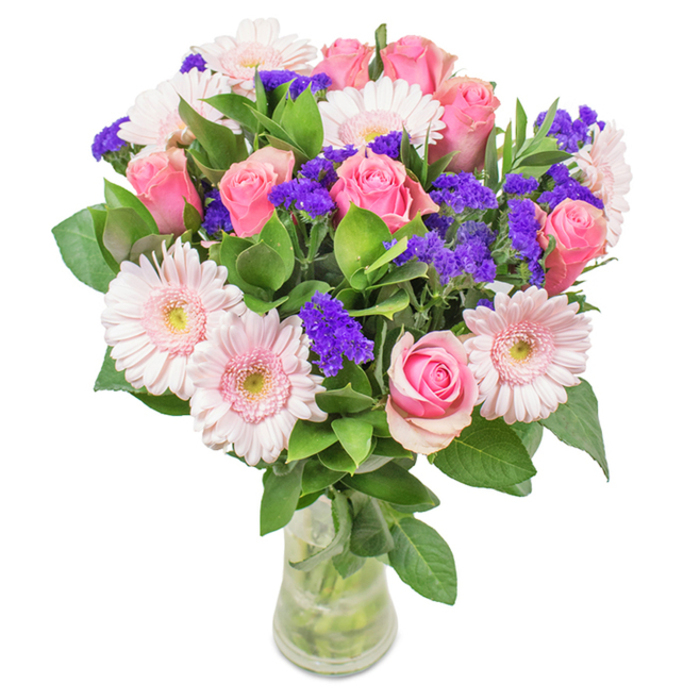 Elegantly composed, this floral bouquet is displayed inside a clear glass vase against a white canvas-the essence of Barkingside's inviting interiors. The main spectacle features around eight pink roses, most petals tightly curled or just beginning to open in supple spirals that promise days of blossoming beauty. About six pale pink gerbera daisies add a soft, understated radiance, each wide head brimming with layers of delicate petals and centers fading to near ivory. Vibrant spikes of purple statice-often sourced fresh from local growers-interject a dynamic pop, accentuating the translation from delicate to bold. The lush base of greenery, reflecting the vibrancy of Barkingside's tree-lined streets, provides texture and depth, heightening the bouquet's freshness and visual harmony. The transparent vase reveals sturdy stems and clear water, reinforcing the bouquet's natural grace and freshly prepared character. Ideal for same-day delivery around Barkingside-be it for birthdays, anniversaries in the heart of Fairlop, or to warm the welcoming ambiance of a local office-this bouquet of roses, gerberas, and purple fillers eloquently conveys moments of joy, gratitude, and celebration.
