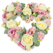 A lovingly crafted heart-shaped wreath stands out clearly against a crisp white background, its pastel hues and natural greenery blending into a soft, harmonious tribute. The heart is densely woven with flowers, starting with creamy yellow and ivory roses that appear throughout the design as gentle focal points. Each rose is open enough to reveal its layered, spiralling centre, the velvety petals curving outward in smooth, rounded forms that give the arrangement a reassuring sense of calm. Nestled between the roses are clusters of light pink carnations, their frilled petals overlapping tightly to build a plush, textured surface, like soft fabric gently gathered along the outline of the heart. Adding depth and contrast, deeper magenta-pink and mauve lisianthus blooms are dotted across the wreath, their cup-shaped, slightly ruffled petals introducing touches of richer colour without overwhelming the gentle palette. Silvery-green eucalyptus leaves weave through the flowers, their rounded shapes and cool tones snaking along the contours of the heart, bringing structure and a whisper of herbal freshness akin to a breeze through the trees near Barkingside's local green spaces. Tiny yellow-green buds poke through at intervals, suggesting new life and quiet hope in the midst of sorrow. The heart shape itself is full and symmetrical, with flowers arranged so closely that the wreath looks abundant and complete from every angle. Ideal as a funeral or memorial tribute for families in Barkingside, this floral heart offers a visual expression of sympathy, love, and cherished memories, providing a peaceful focal point during services and moments of reflection.